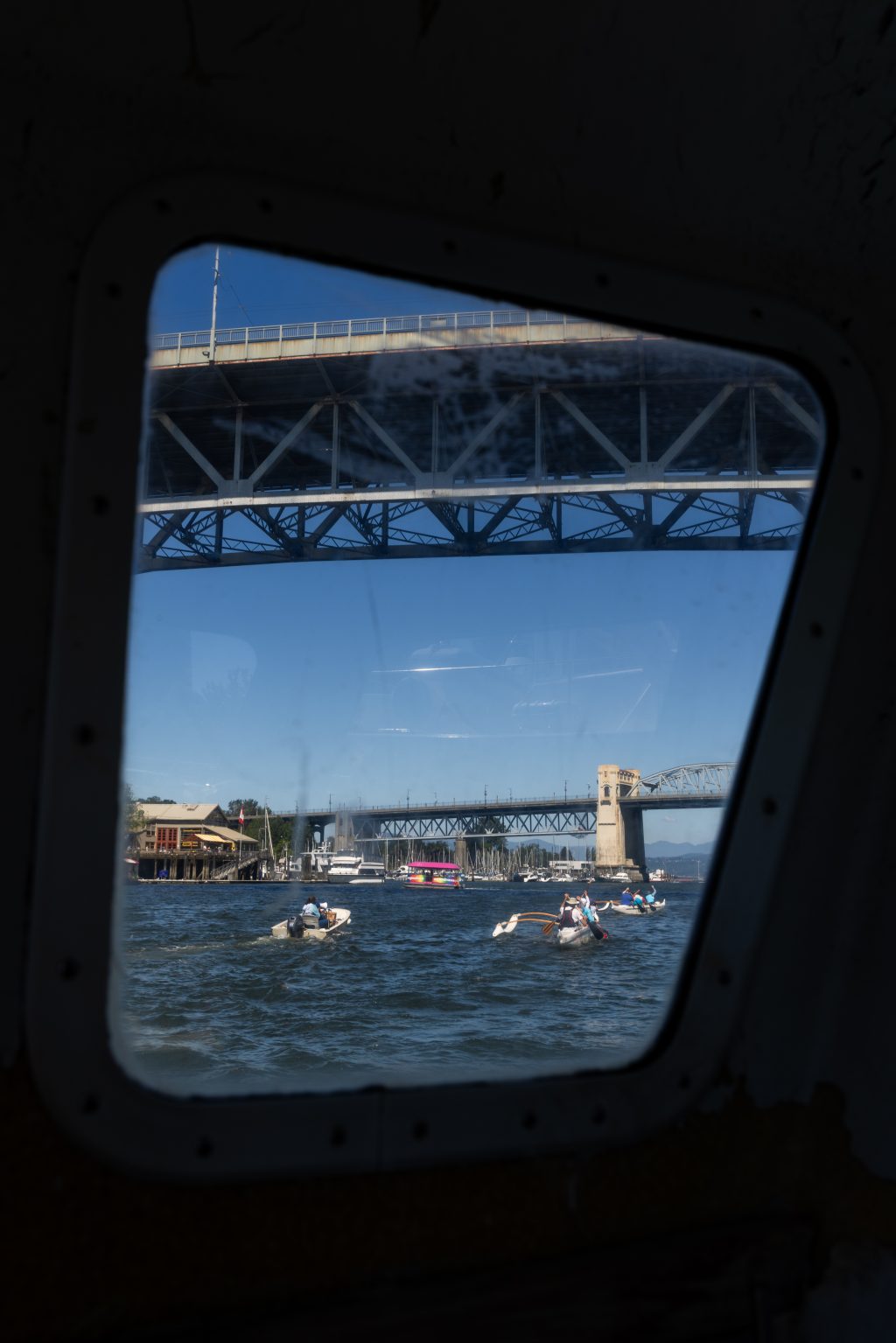 A view through a boat window of False Creek and a bridge, with a few small boats on the water