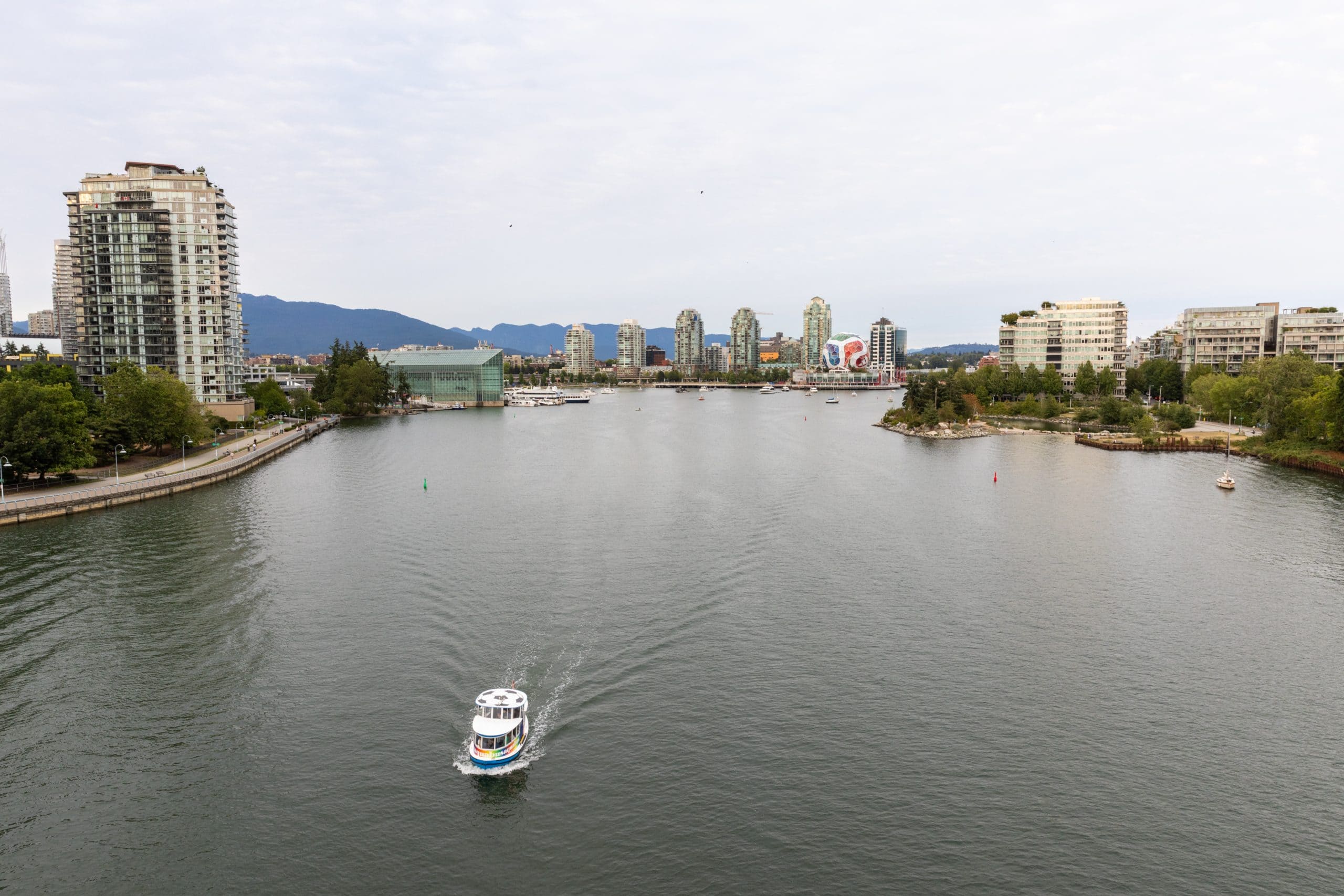 A view of False Creek from the Cambie Bridge, as a small ferry boat sails through the empty harbour.