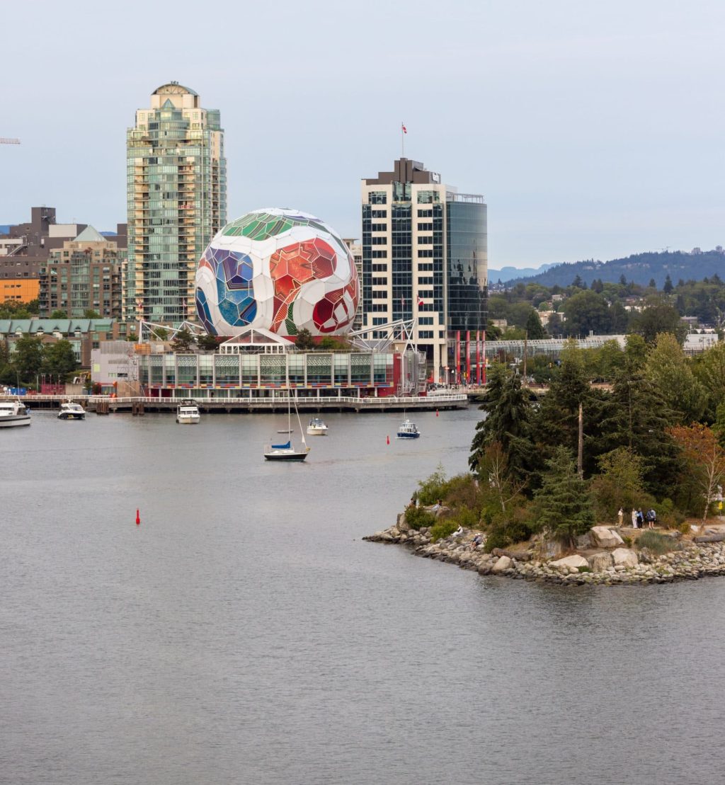 A view of False Creek, with Science World in the background wrapped to look like a FIFA soccer ball, and a small number of boats on the water.