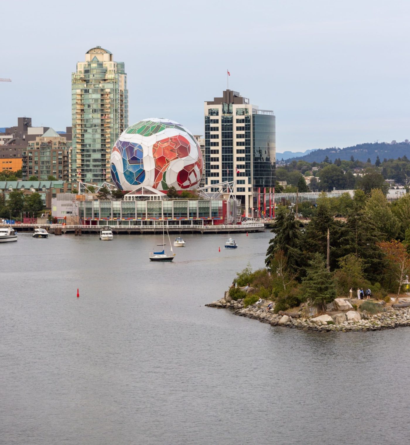 A view of False Creek, with Science World in the background wrapped to look like a FIFA soccer ball, and a small number of boats on the water.