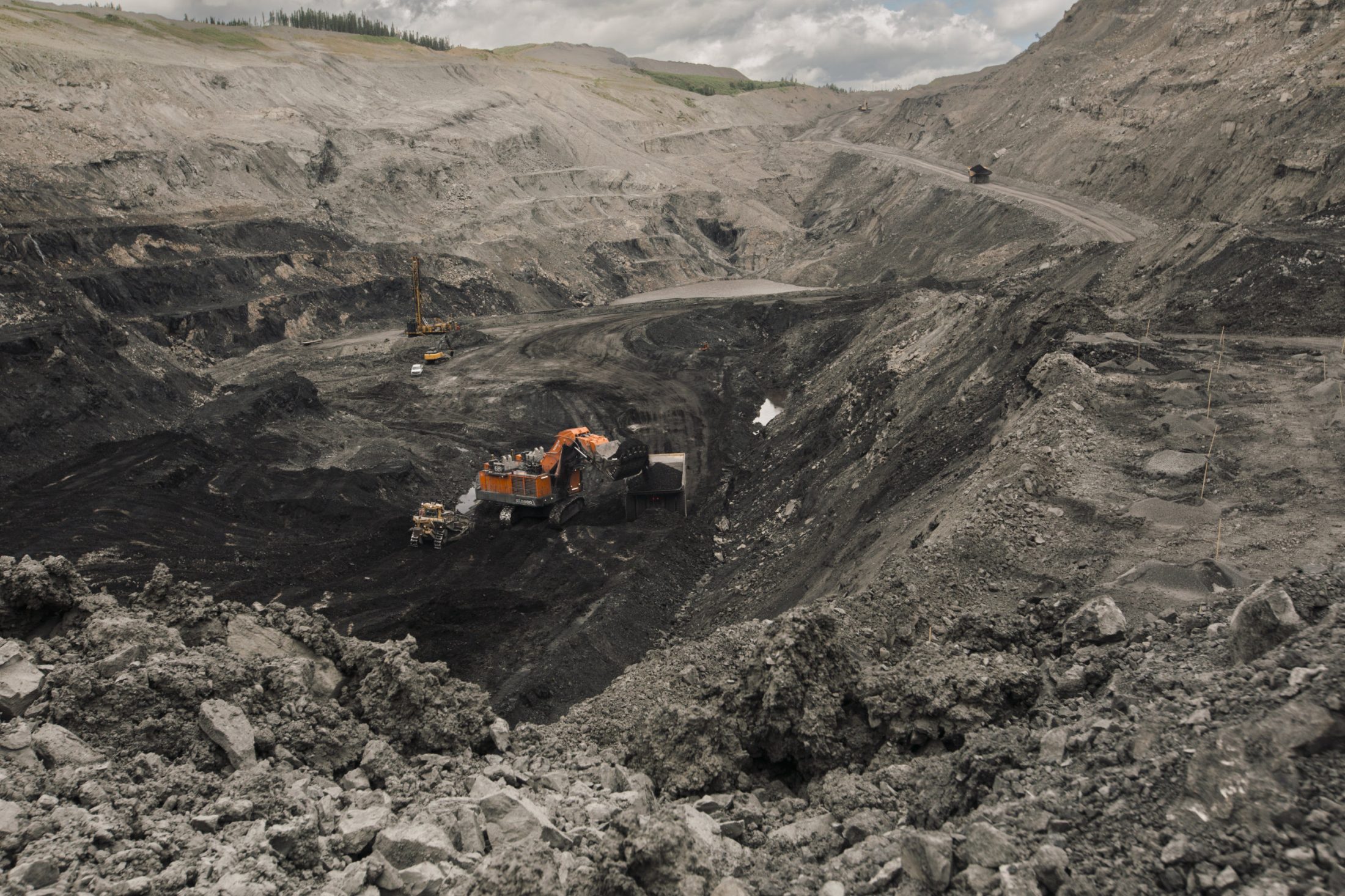 A tractor digs into dirt at the bottom of an open-pit mine.