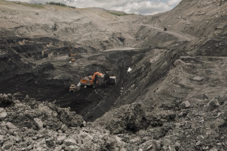 A tractor digs into dirt at the bottom of an open-pit mine.