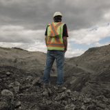 A worker wearing a hard hat, reflective vest and jeans overlooks mine operations at the Coal Valley mine south of Edson, Alberta.