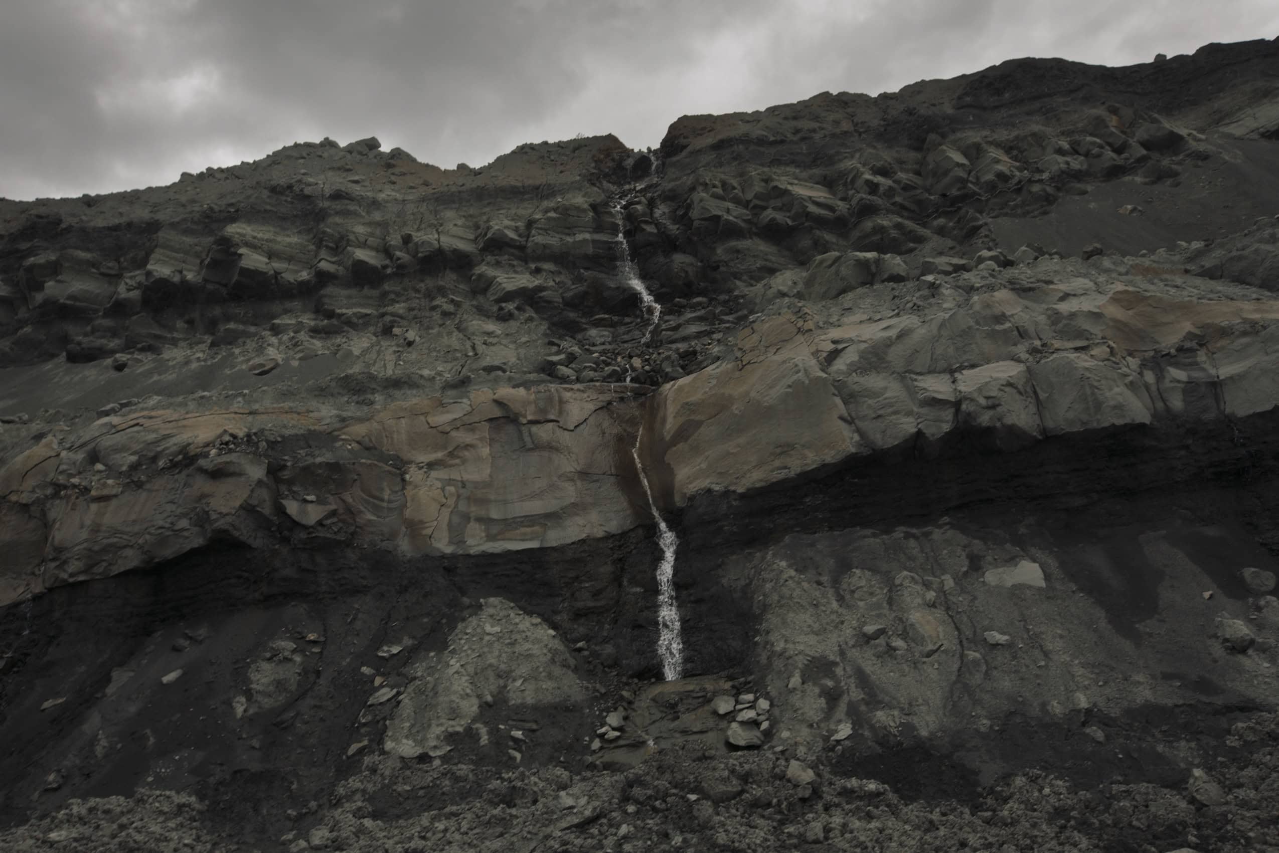 A small trickle of a waterfall runs down along the edge of a steep rock wall in an Alberta coal mine.