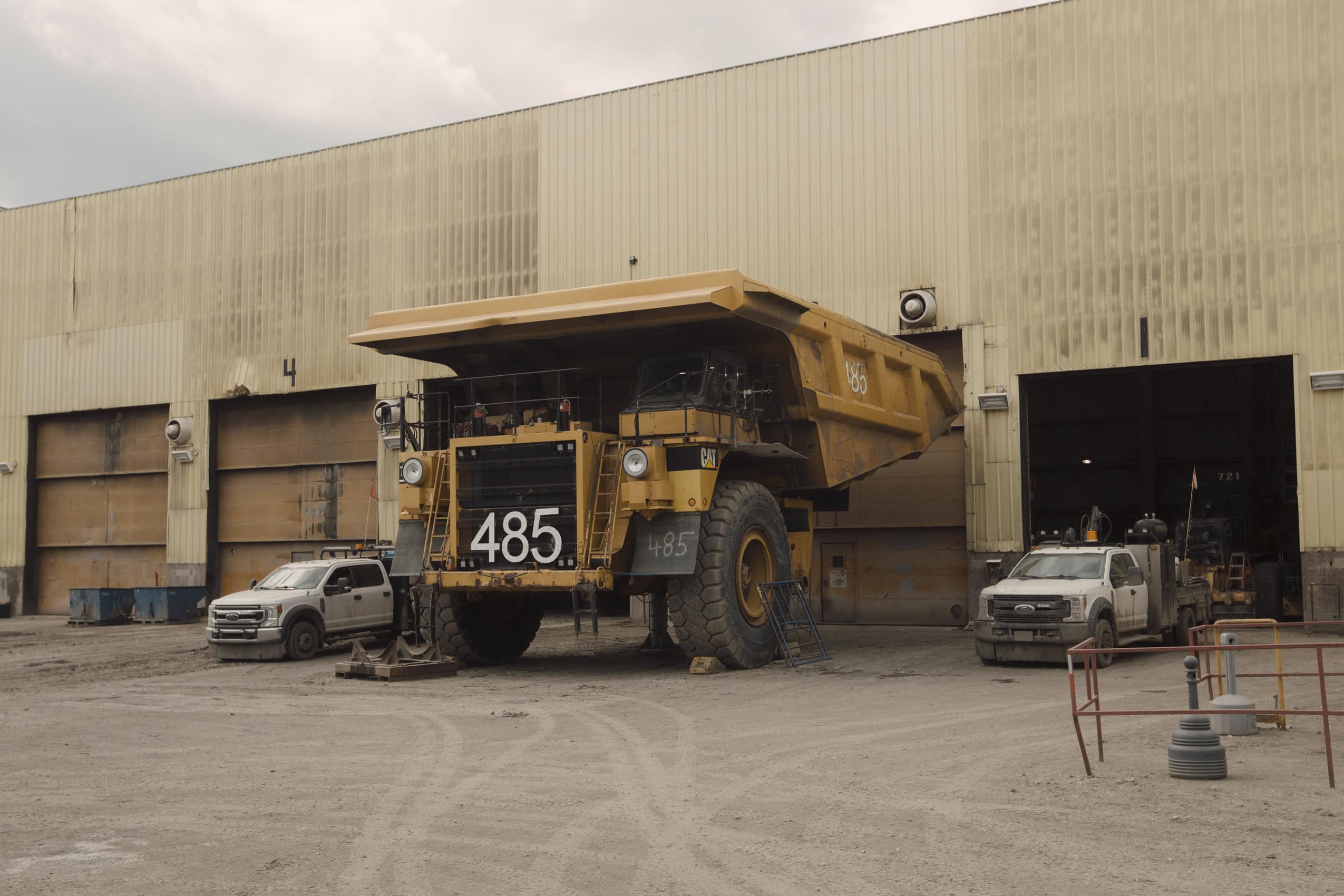 A mining dump truck dwarfs two pickup trucks while awaiting repairs at the Coal Valley mine south of Edson, Alberta.