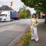 Michelle Brown-Colistro stands by the side of a road, as a container truck drives by.