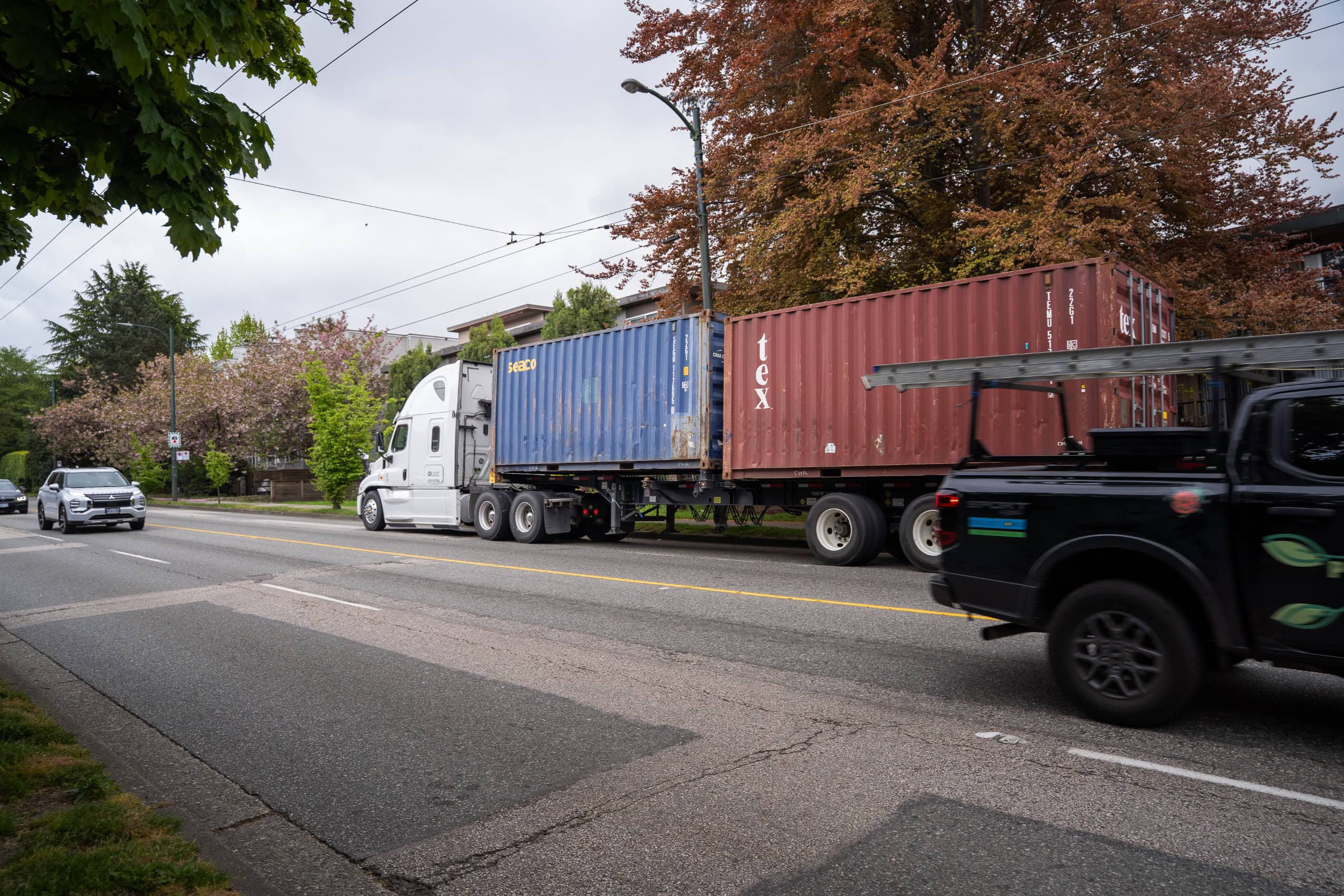 A freight truck drives on a busy city highway.