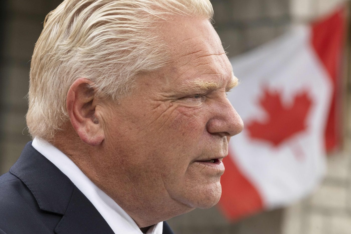 Doug Ford's face up close with a Canadian flag in the background
