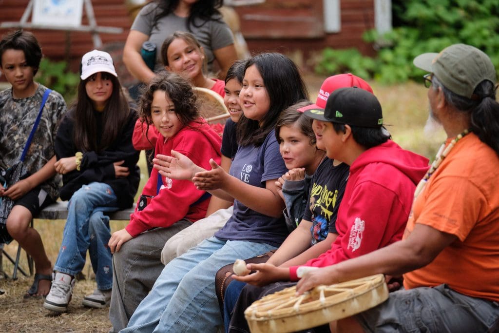 Youth participating in cultural activities at an outdoor camp setting in British Columbia.