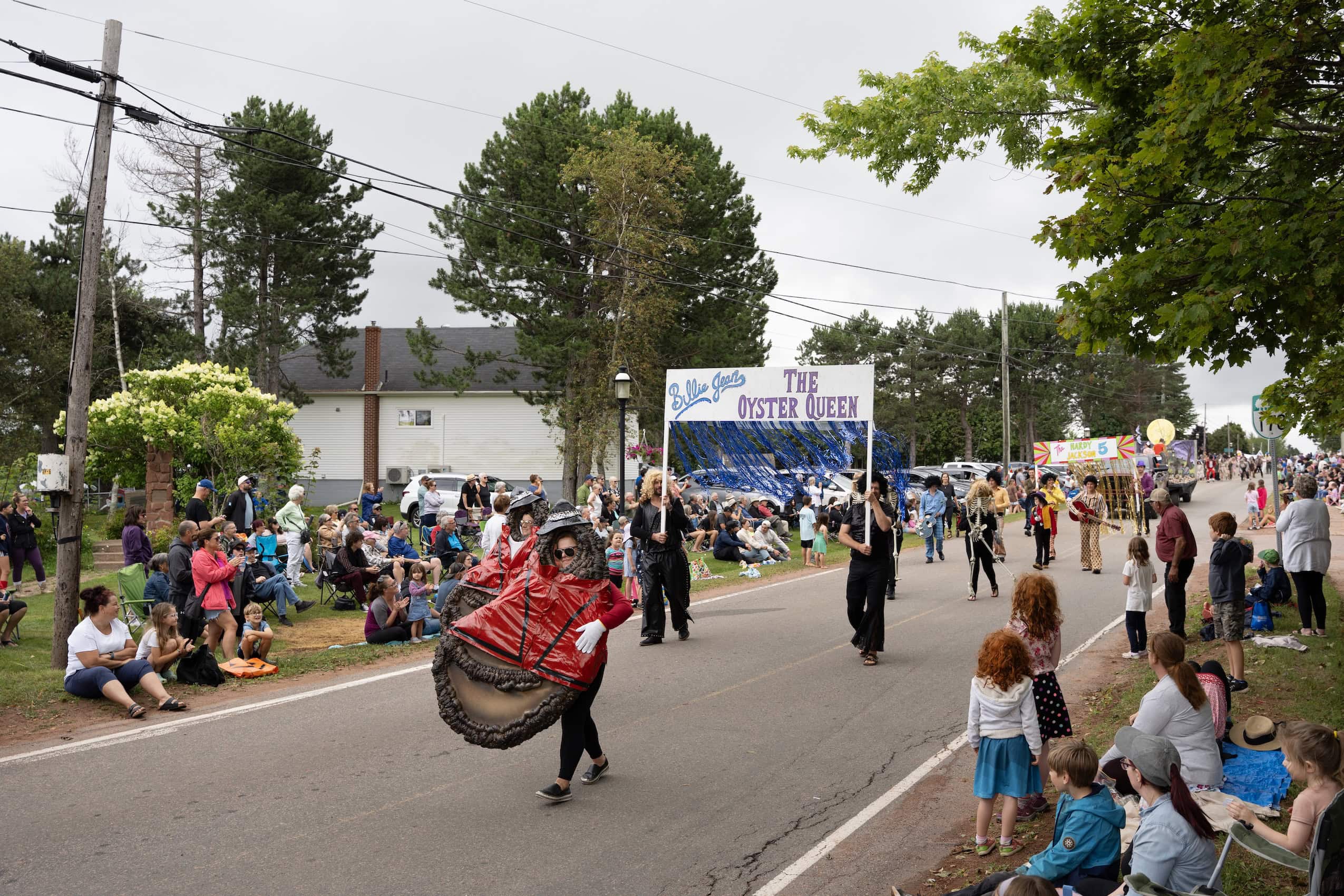 A parade with people dressed up as oysters and a sign reading "Billie Jean, the Oyster Queen."