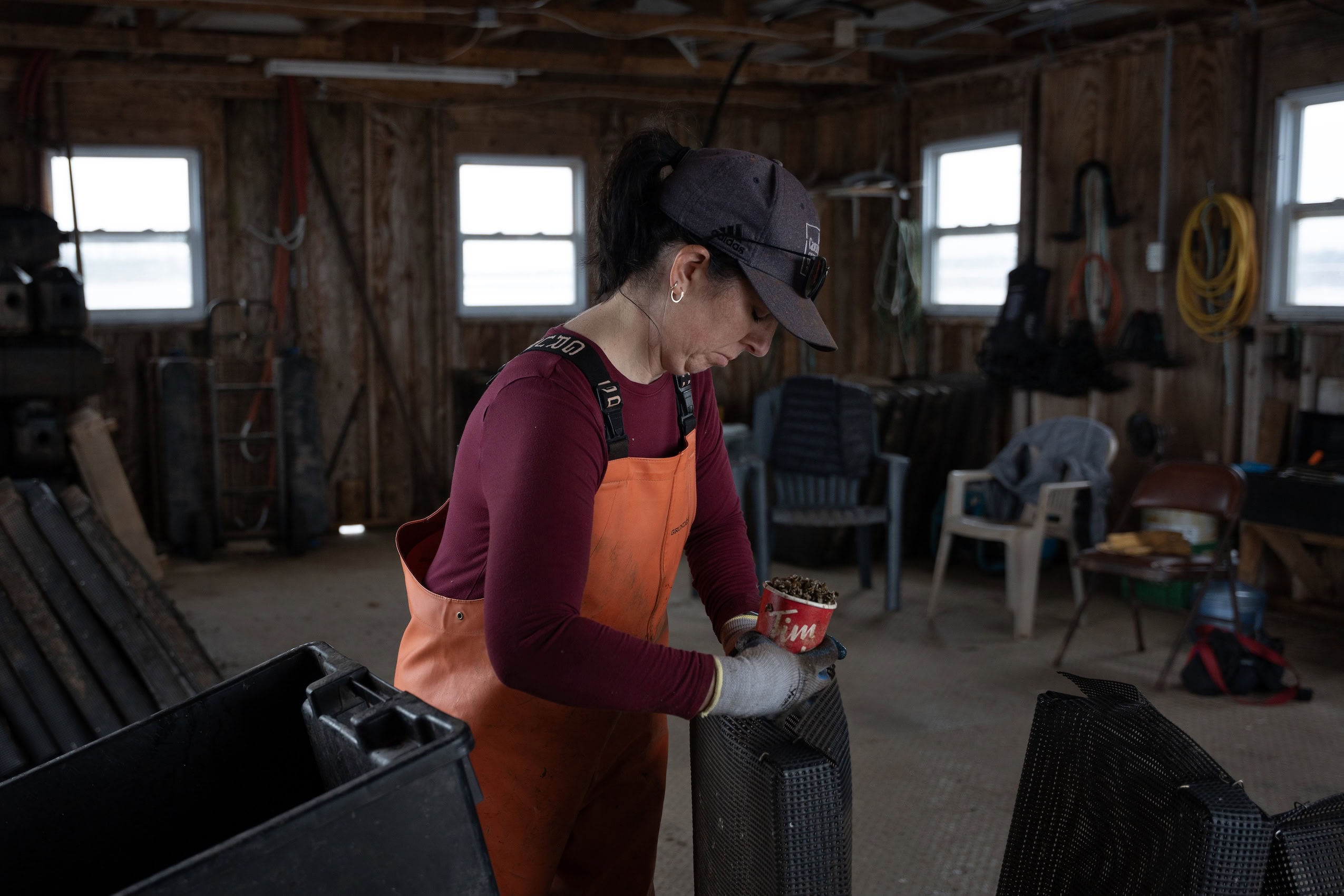 Monique Horne filling a Tim Hortons cup with oyster seeds on her boat.