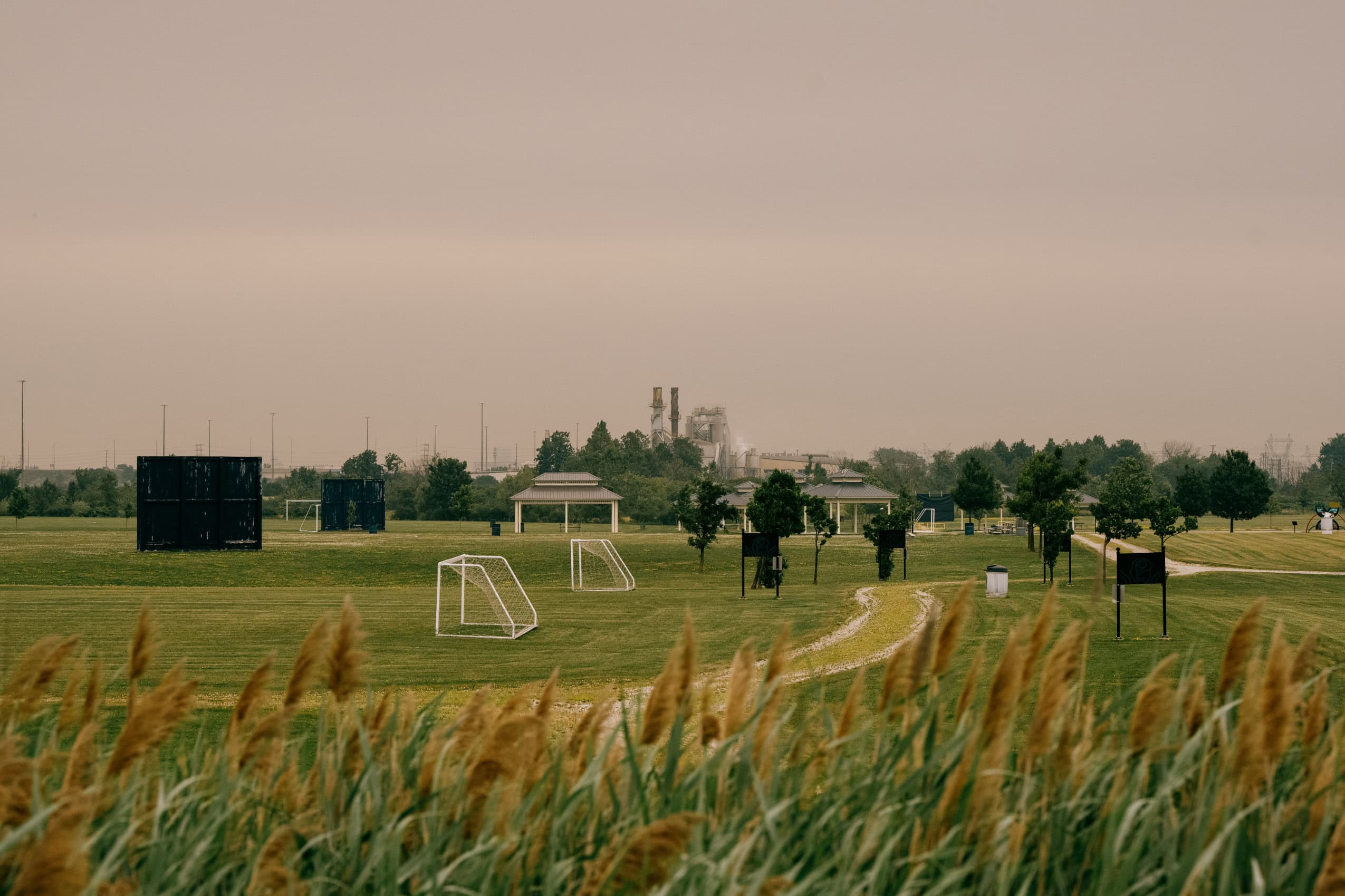 Soccer fields in Brampton, Ontario, with the smokestacks of the Emerald Energy from Waste incinerator rising up from the horizon.