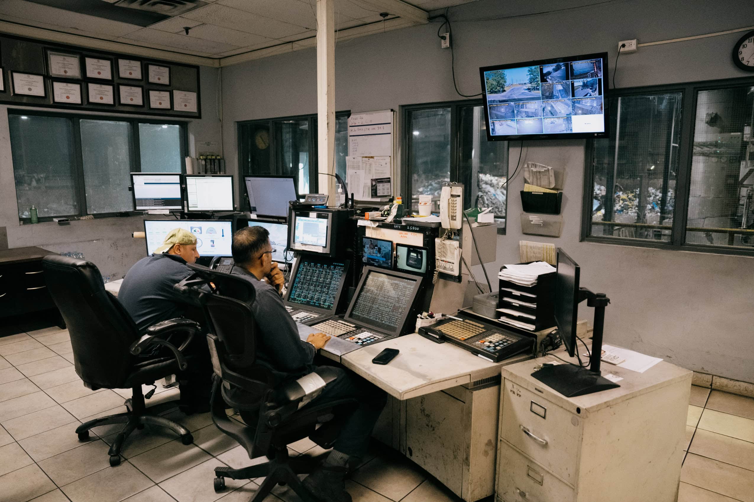 Two engineers monitor operations inside of a control room at an industrial facility.
