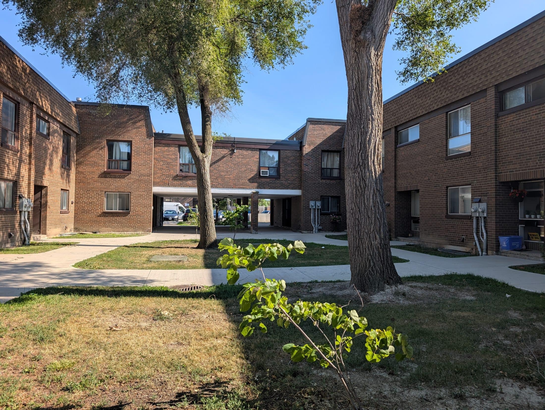 A housing complex is seen with minimal trees and portable air conditioners