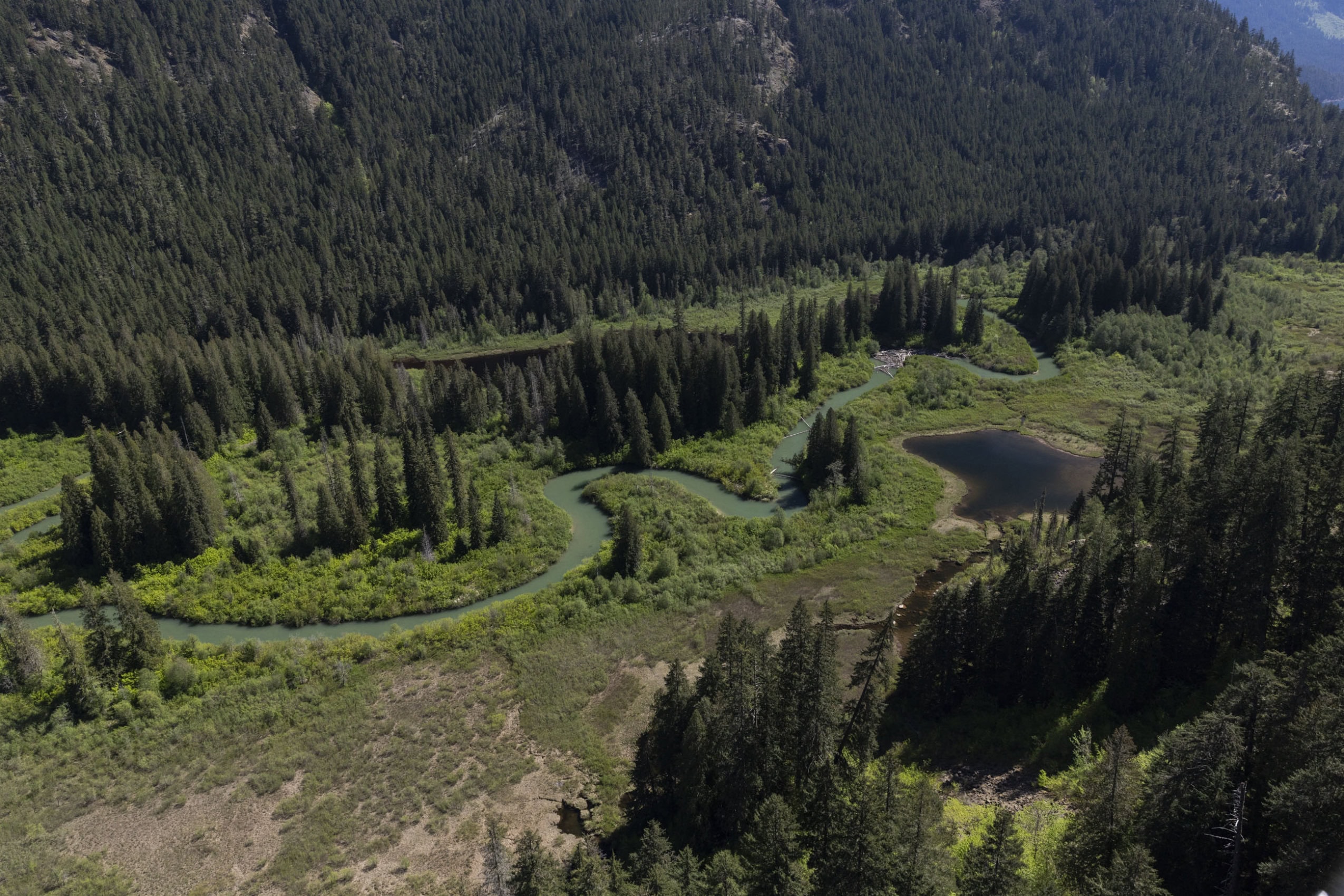 A small river meanders through a valley in a mountainous area.