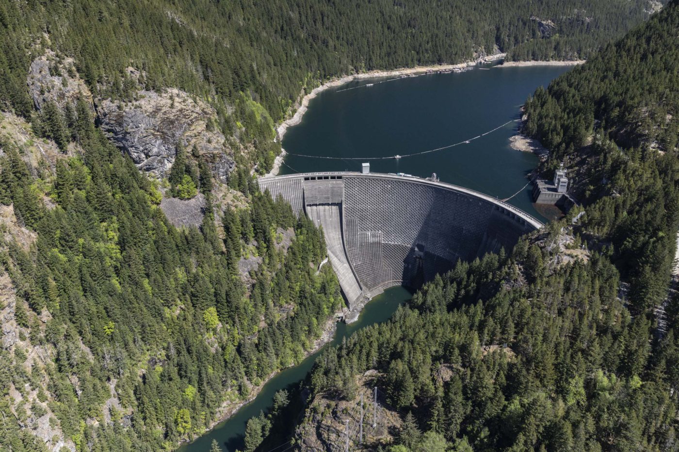 An aerial view of the Ross Dam on the Skagit River. The massive dam is holding back an artificial reservoir behind it.