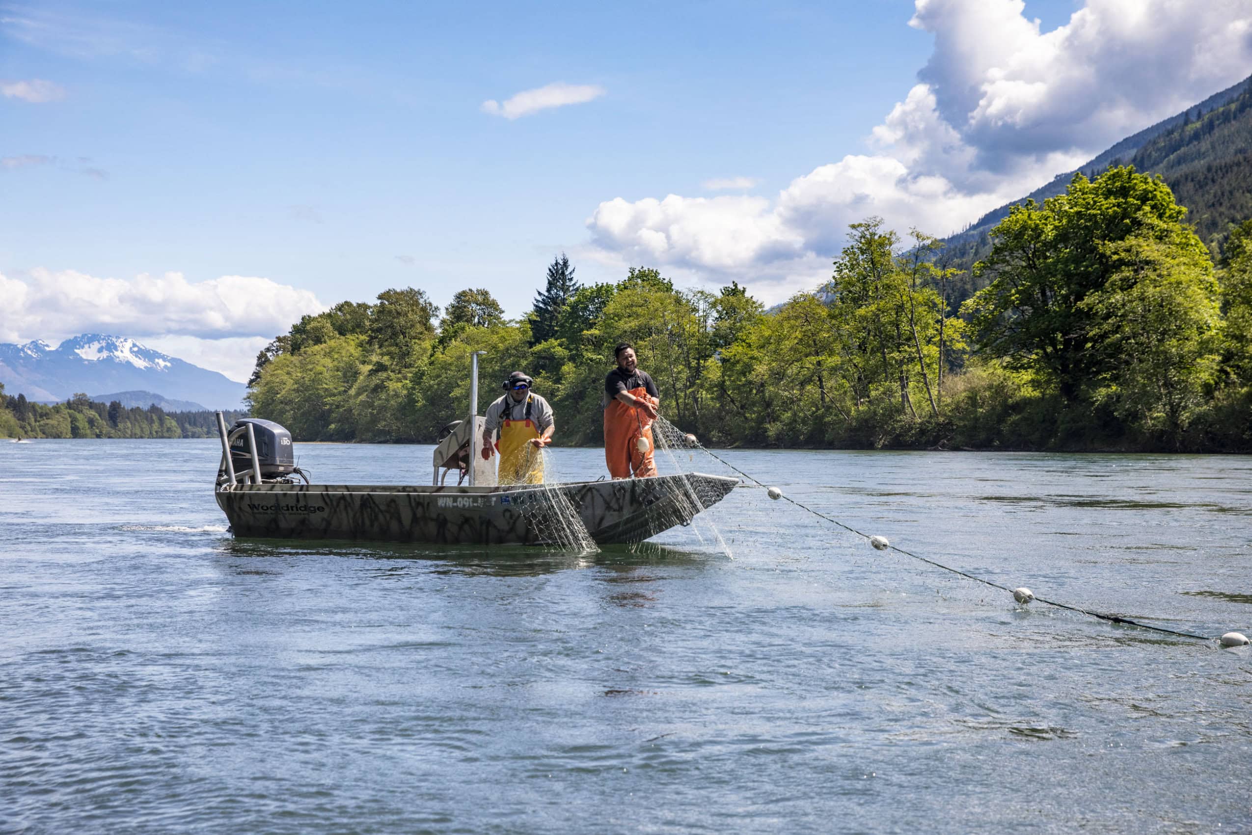 Two fishers on the Skagit River haul a net back into their boat.