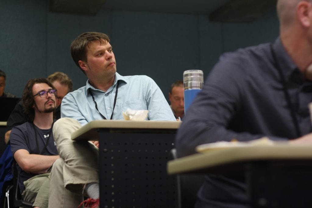 A man sits at a desk in a conference.