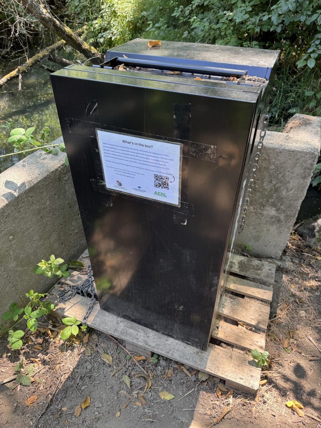 An automated water collection machine along the edge of a riverbank.