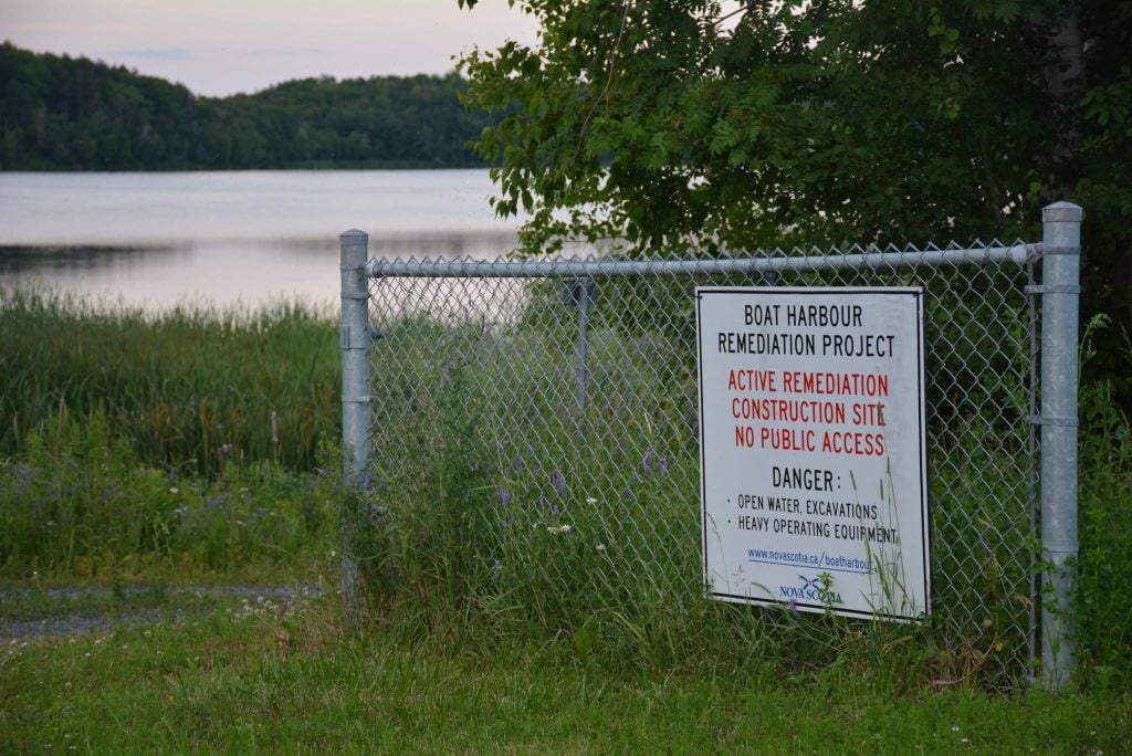 A sign reading "Boat Harbour Remediation Project" in front of a body of water