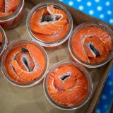 Jars of sockeye salmon sit on a table, about to canned in a pressure cooker.