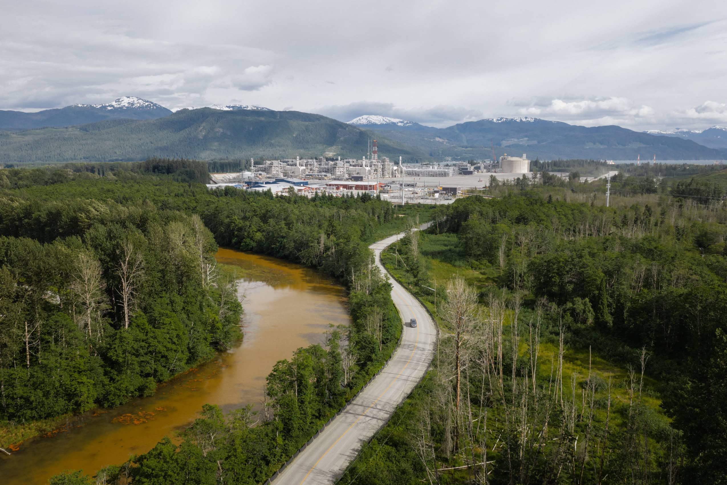 An orangey brown river and road lead into an industrial plant