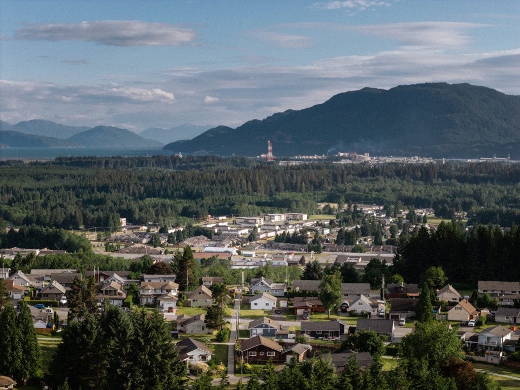 A zoomed out view of a town with a small LNG flare in the background