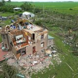 Bricks surround a dilapidated house with the roof torn off by a tornado that hit the area.