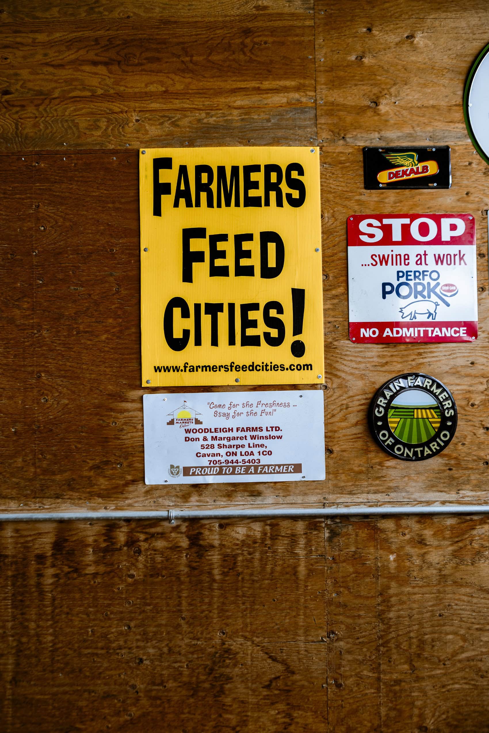 A sign on a wall that reads Farmers Feed Cities, surrounded by smaller signs