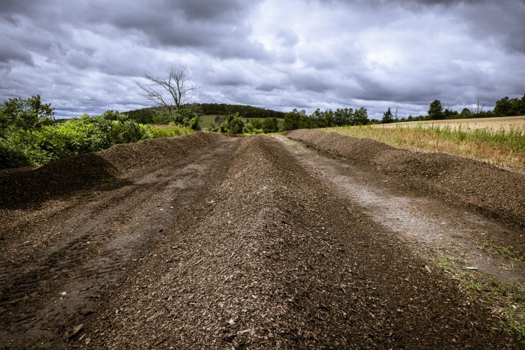 A farm road into rolling hills under a cloudy sky