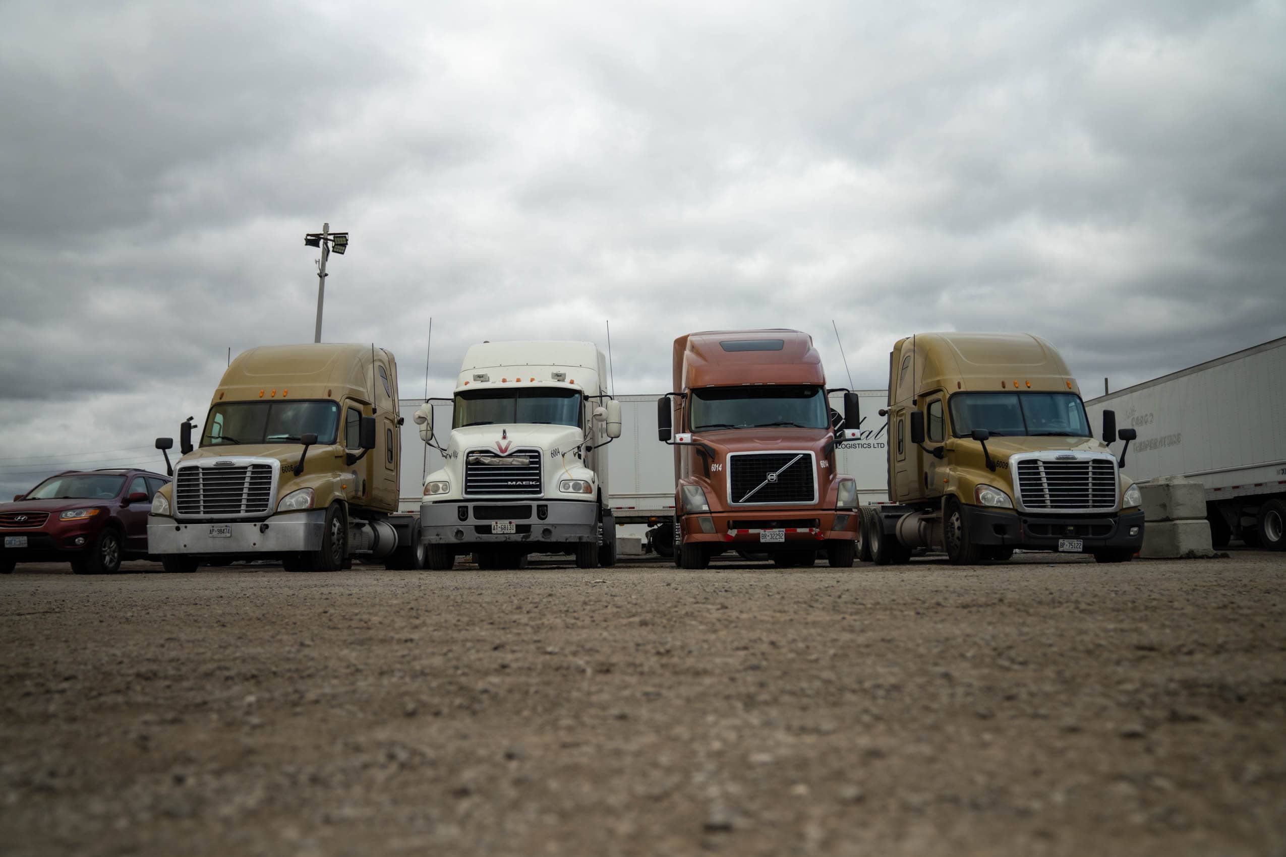 Four tractor-trailer trucks parked in a lot.