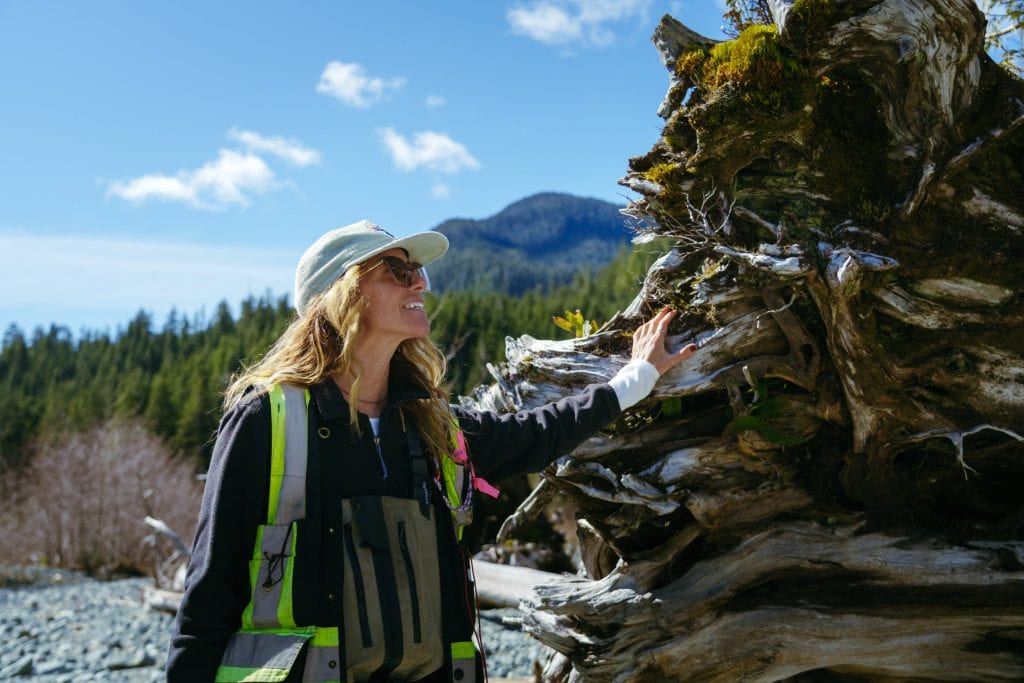 Jessica Hutchinson smiles as she touches an old growth tree that is lying, uprooted, on the ground.