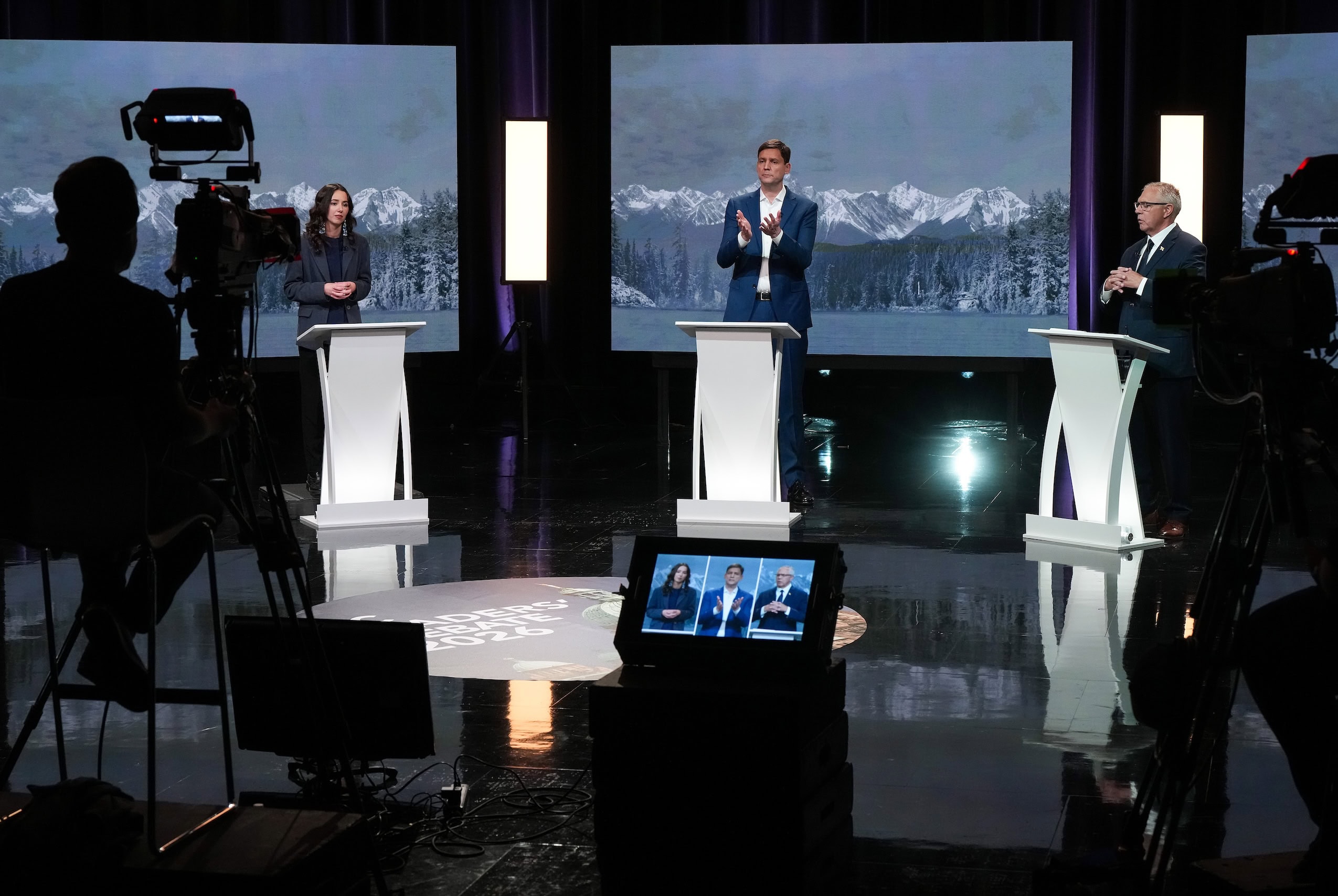 Three British Columbia party leaders stand at lecterns during a debate for the 2026 provincial election.