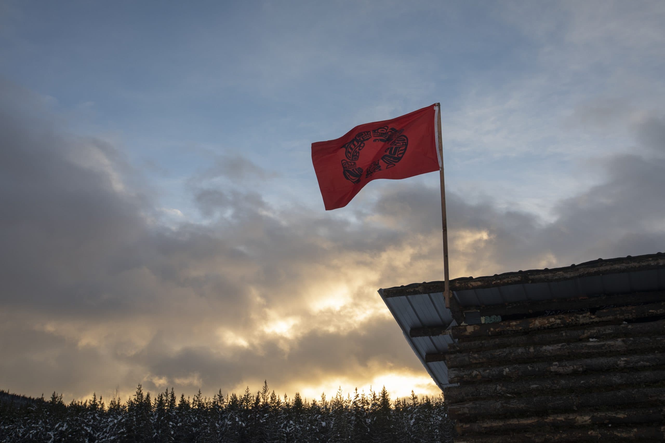 A red GidimtÕen flag flies on the camp kitchen as the sun rises.