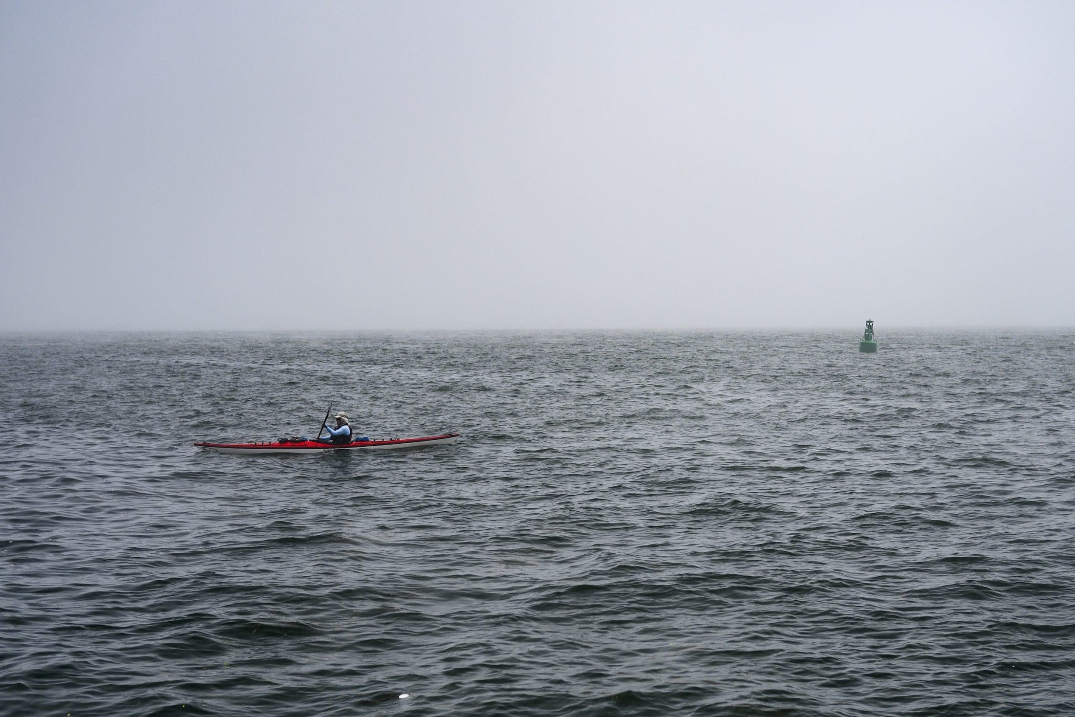 A kayaker paddles on Lake Ontario during a heavy fog.
