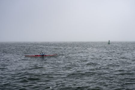 A kayaker paddles on Lake Ontario during a heavy fog.