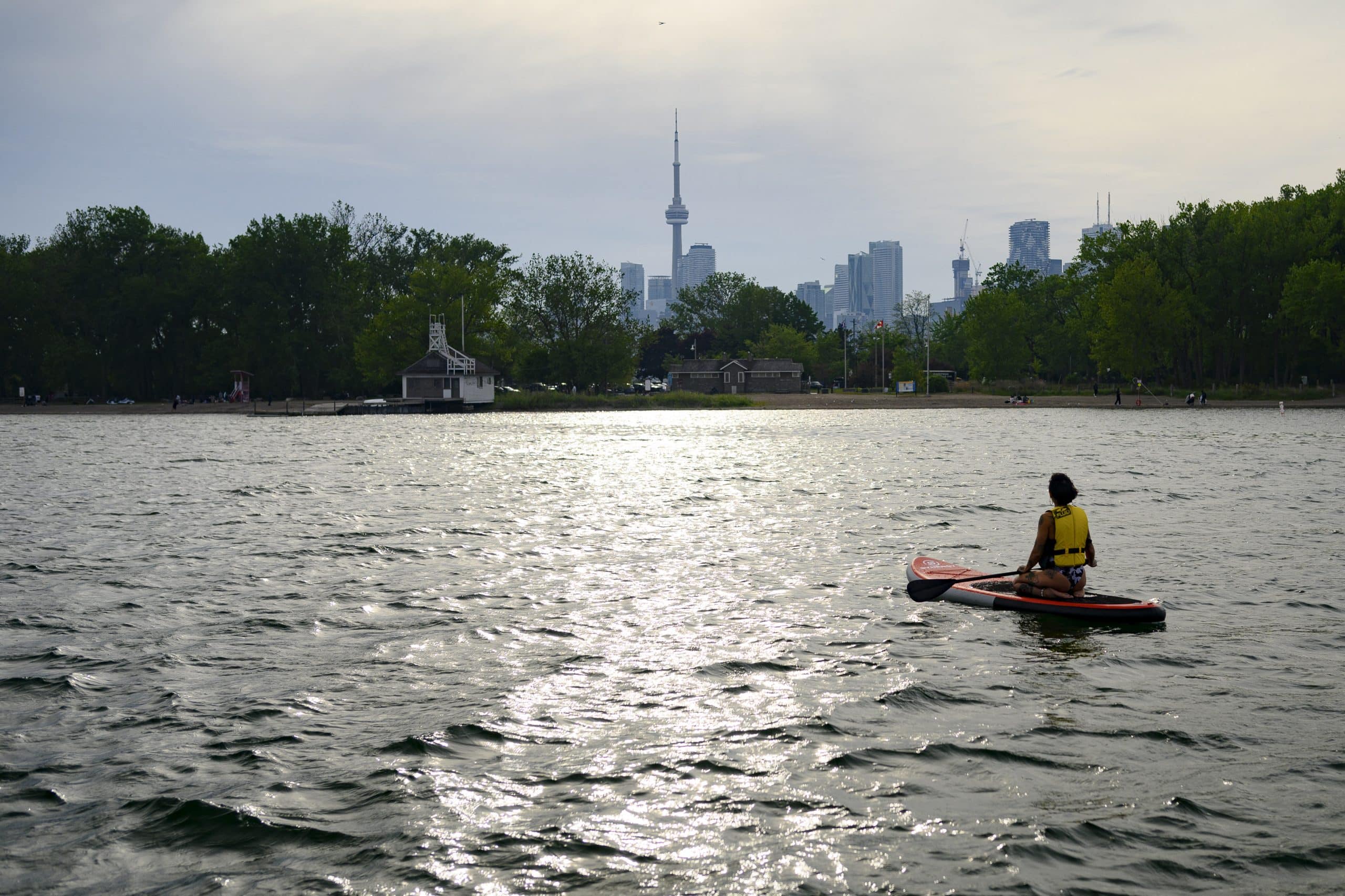 A picture of Lake Ontario with a background of the Toronto skyline, a person sits in a canoe