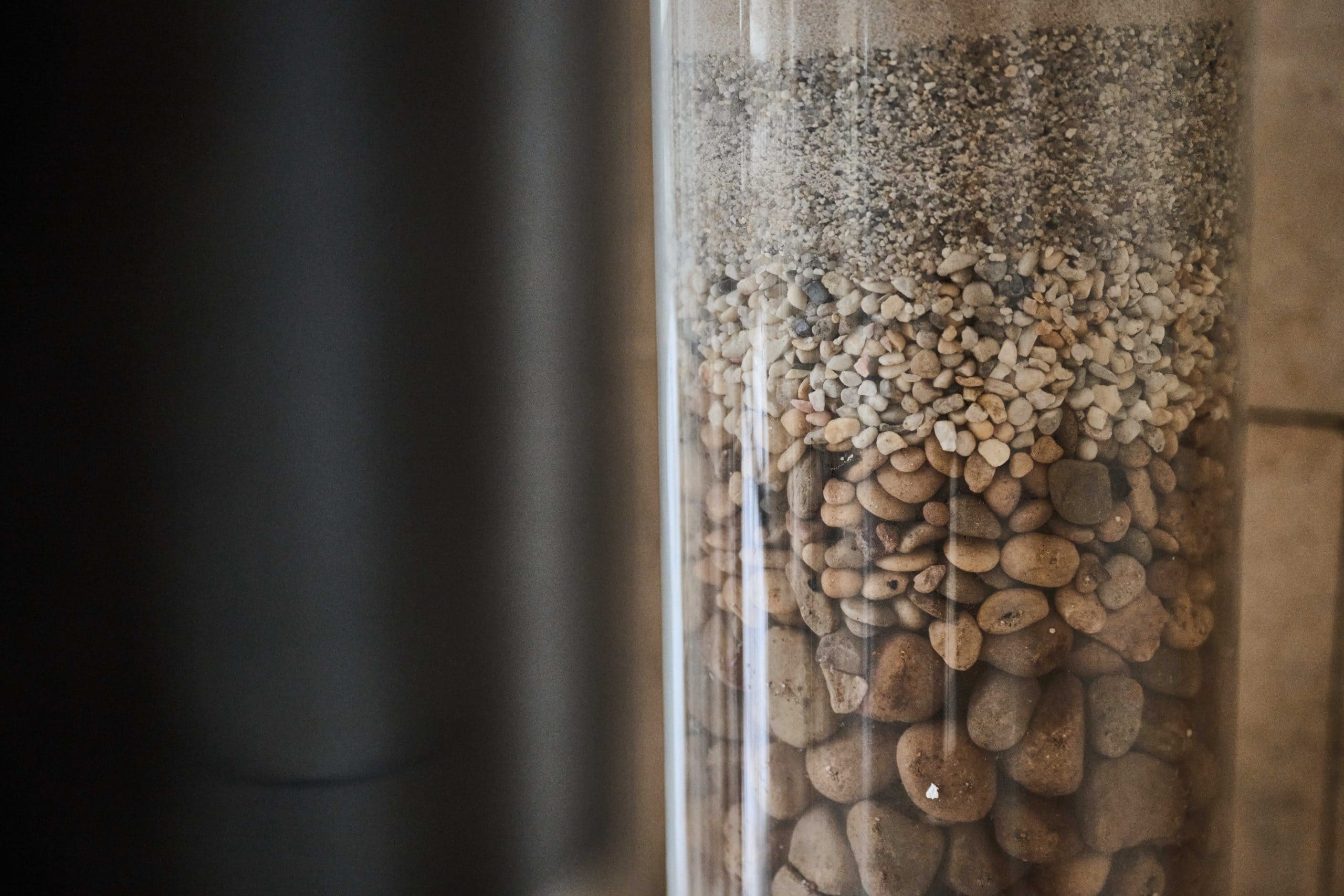 Two plastic tubes containing sand, pebbles and a crushed type of coal.