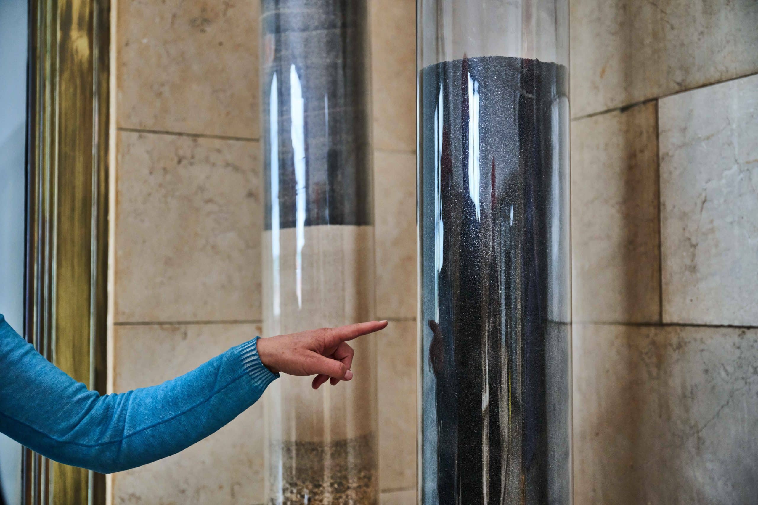 Two plastic tubes containing sand, pebbles and a crushed type of coal.