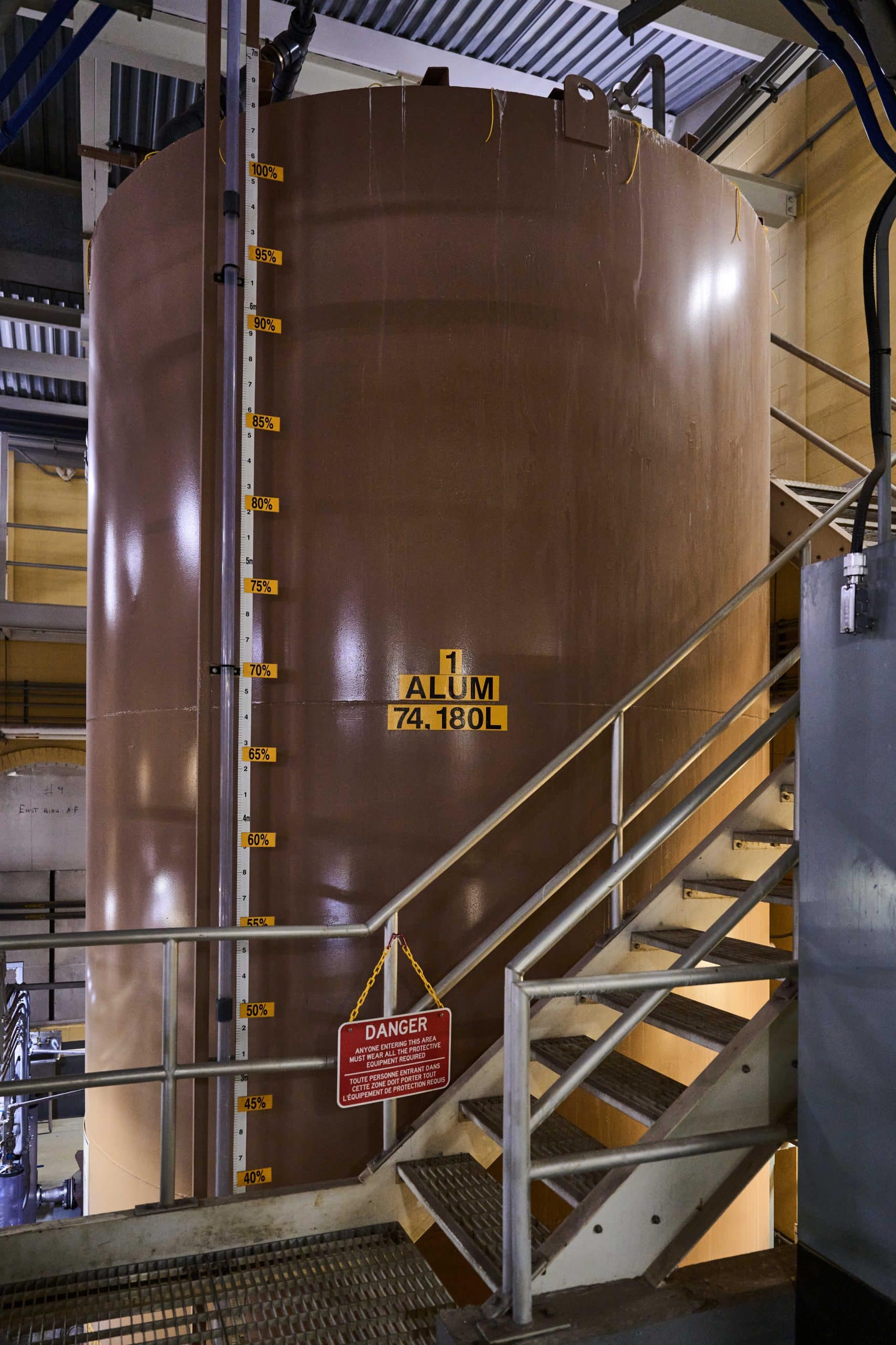Large brown floor to ceiling tanks marked "alum" and "silica" in an industrial looking room.