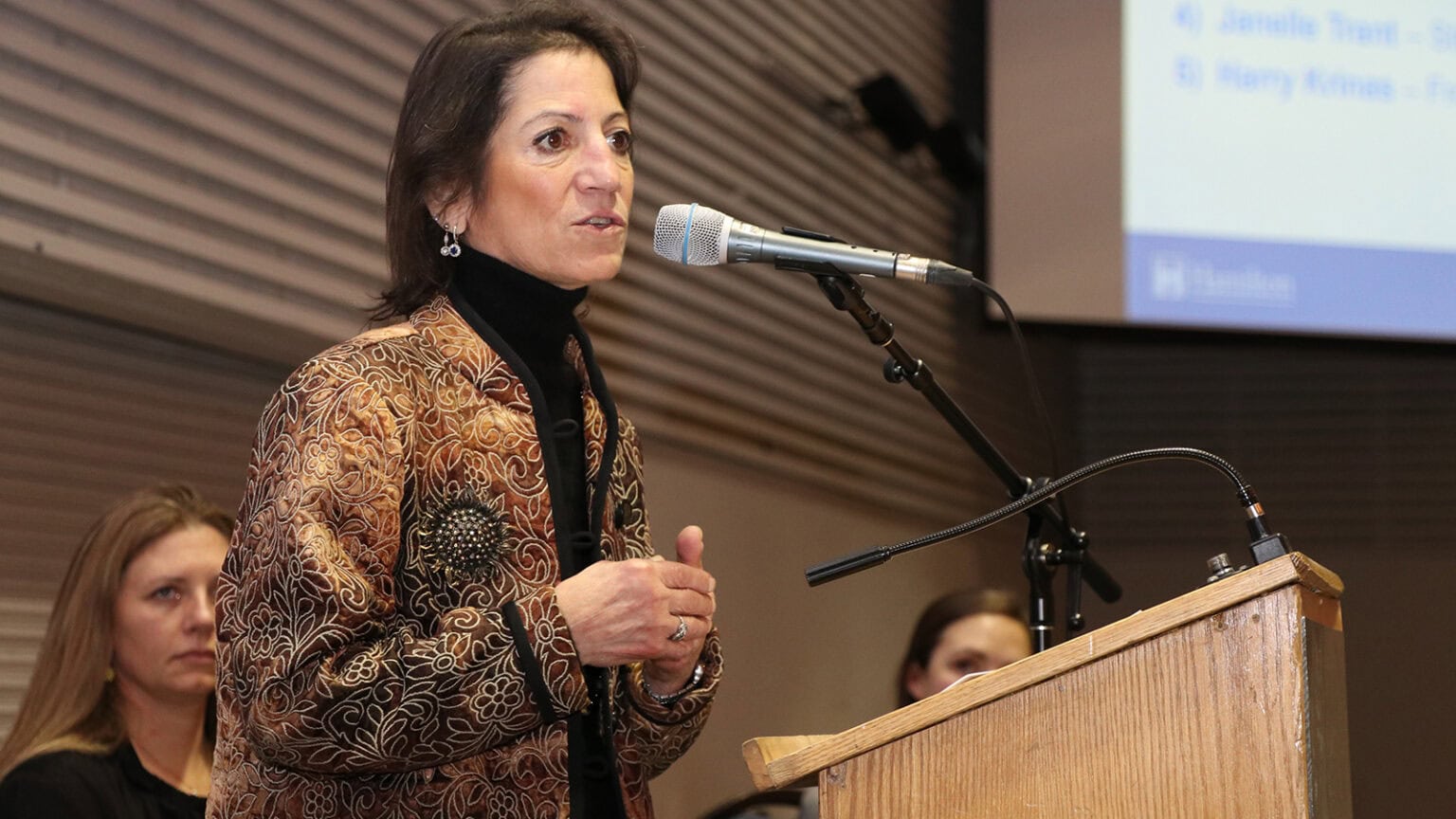 Gail Krantzberg stands behind a lectern and speaks into a microphone.