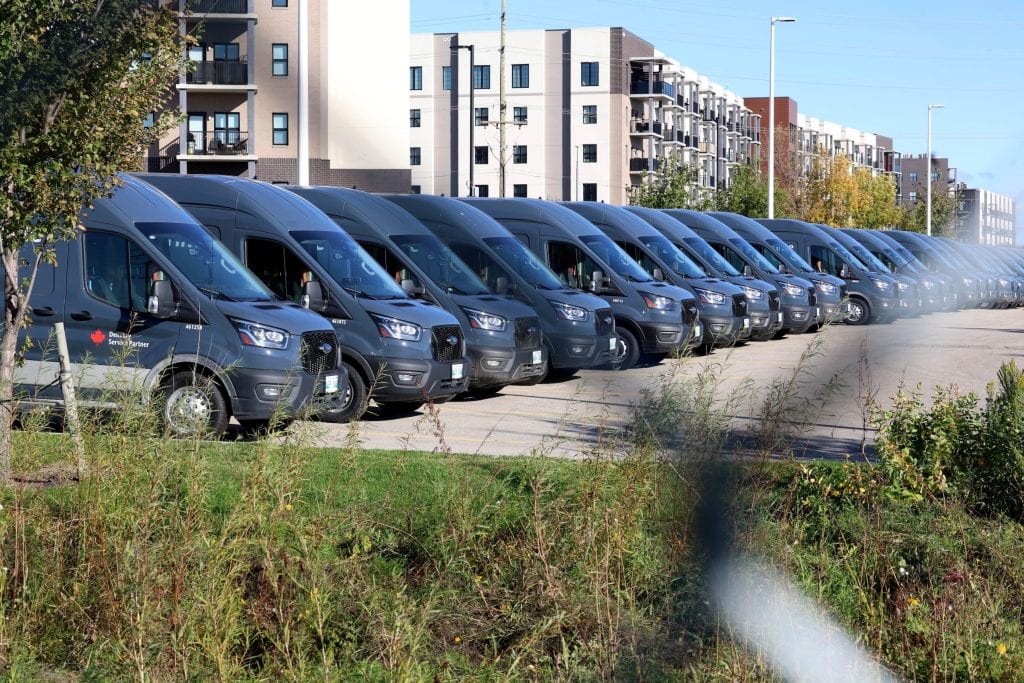 A row of delivery vans parked side by side in a parking lot.